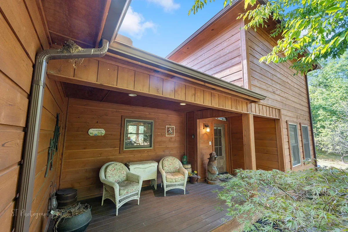 This image features the front porch of Kim's Cove cabin, with inviting seating, a wooden exterior, and decorative wall accents. The porch is surrounded by natural beauty, creating a welcoming first impression and hinting at the relaxing and social atmosphere that awaits guests.